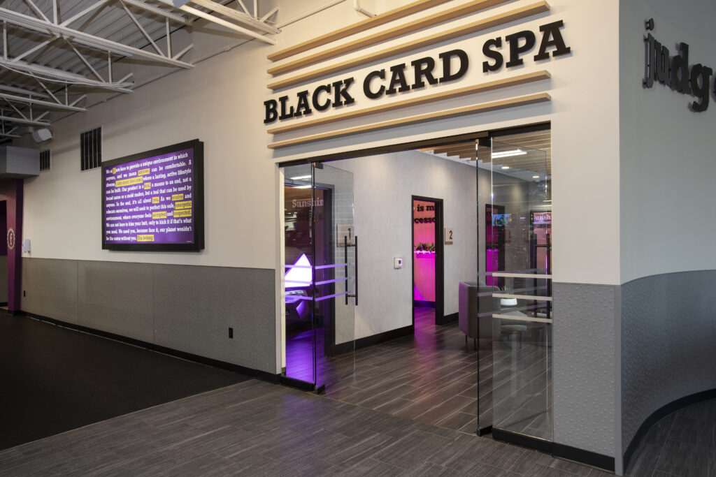 Planet Fitness "Black Card Spa" labeled on white wall looking inside with neon lighting